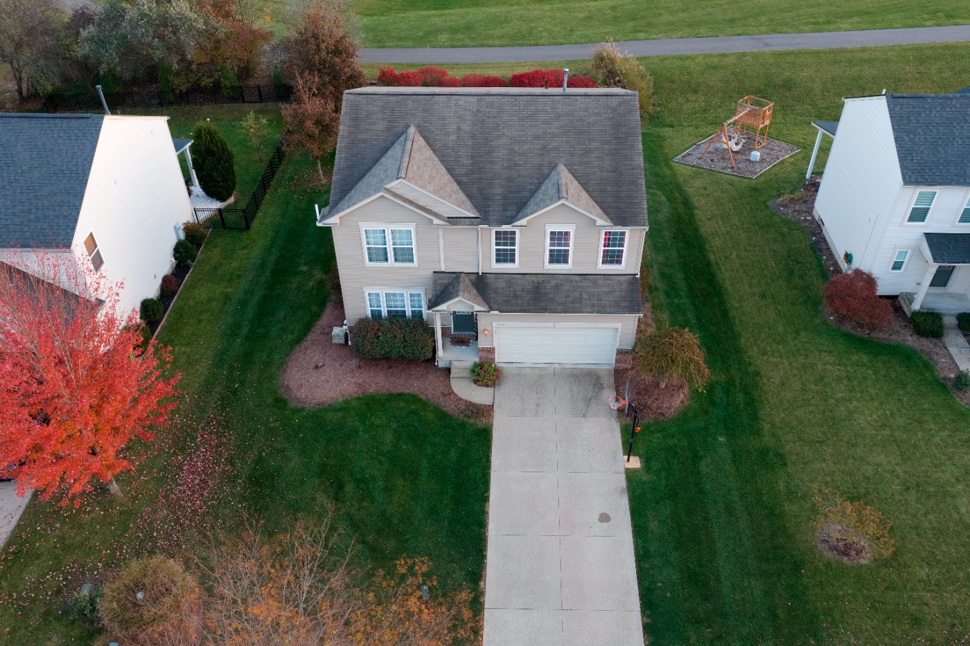 Elevated corner view of the house showing the roofline, side yard, landscaping and neighboring homes