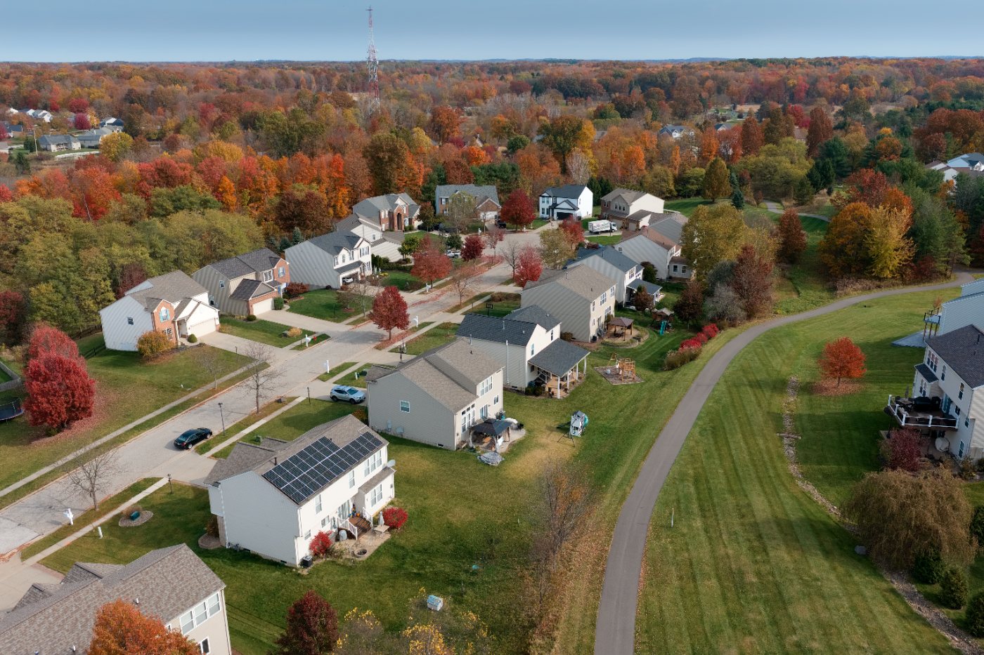 Wide aerial view of the neighborhood in fall color, with streets, homes and a walking path