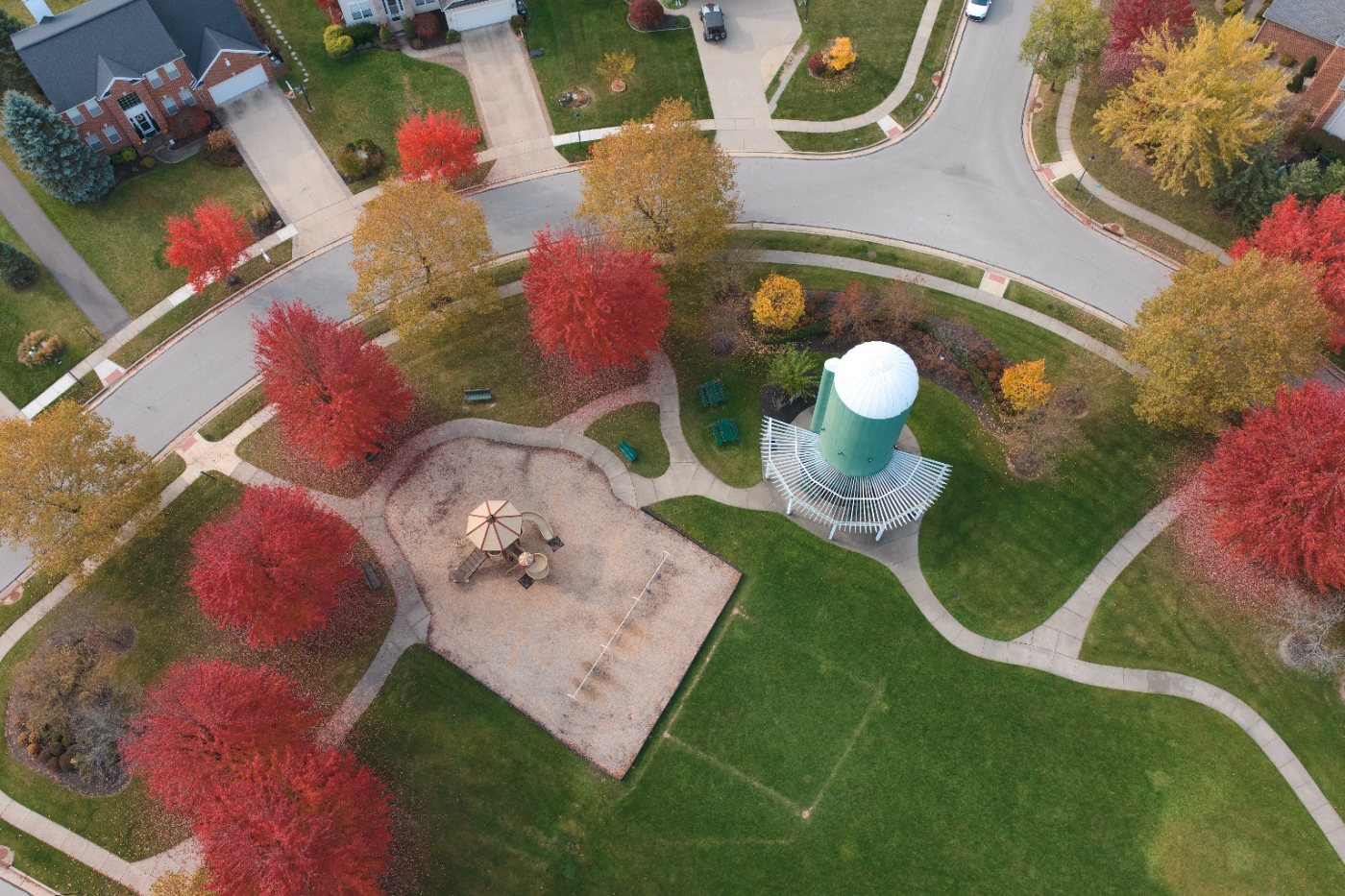 Overhead view of the neighborhood park with a playground, pavilion and paths among red maples