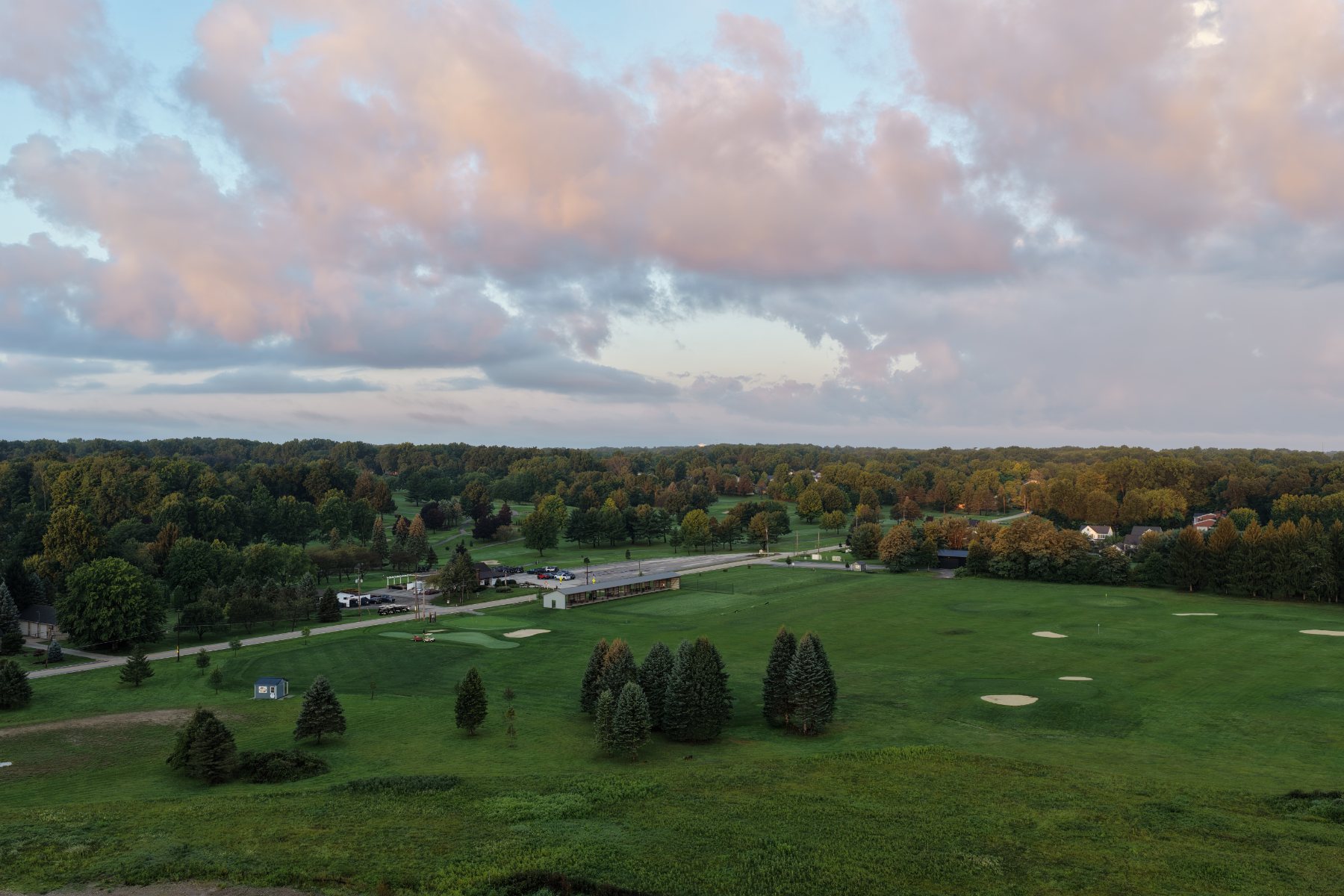 Wide aerial view of a golf course and its clubhouse at dawn