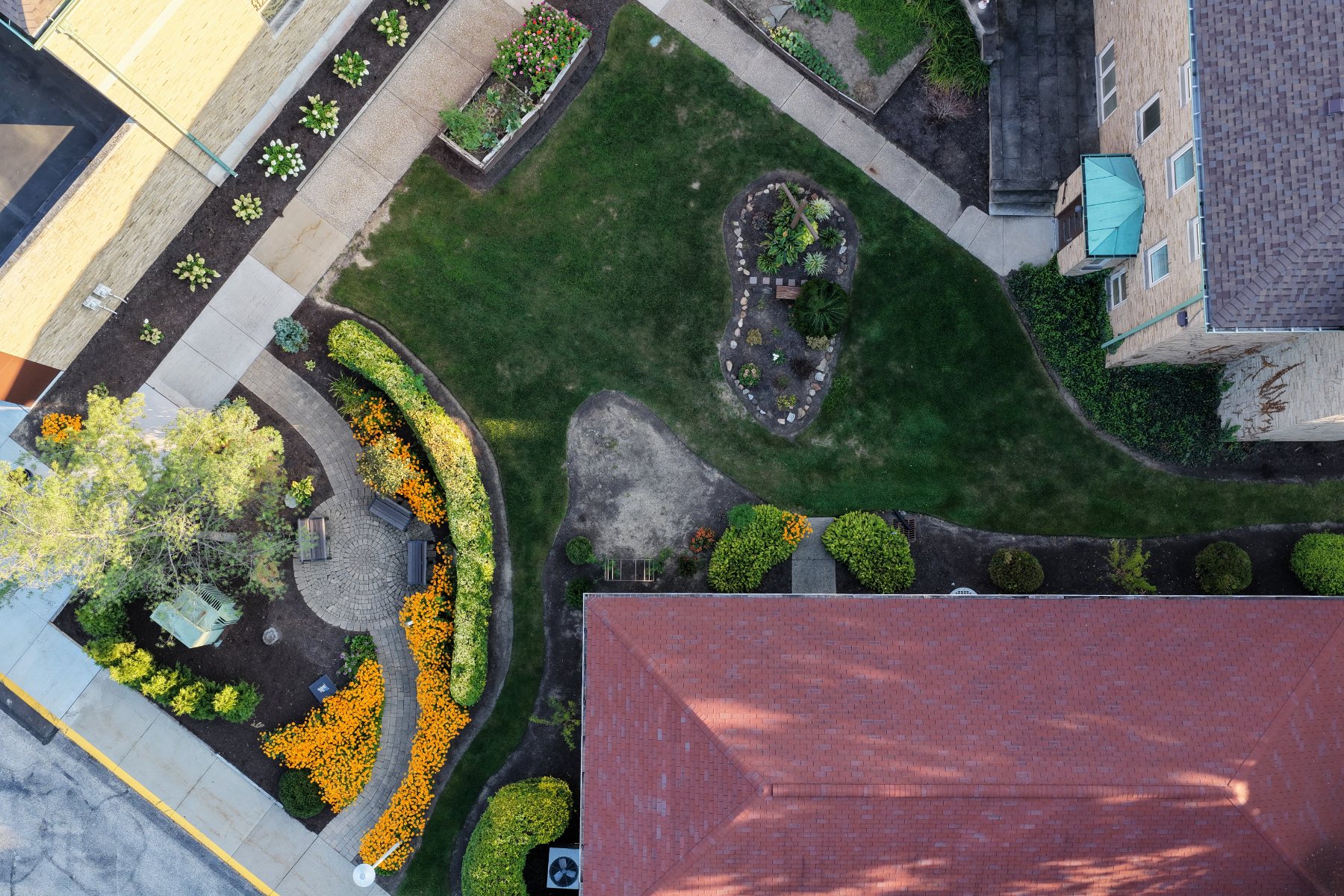 Straight-down aerial view of a courtyard, planting beds and adjoining roofs